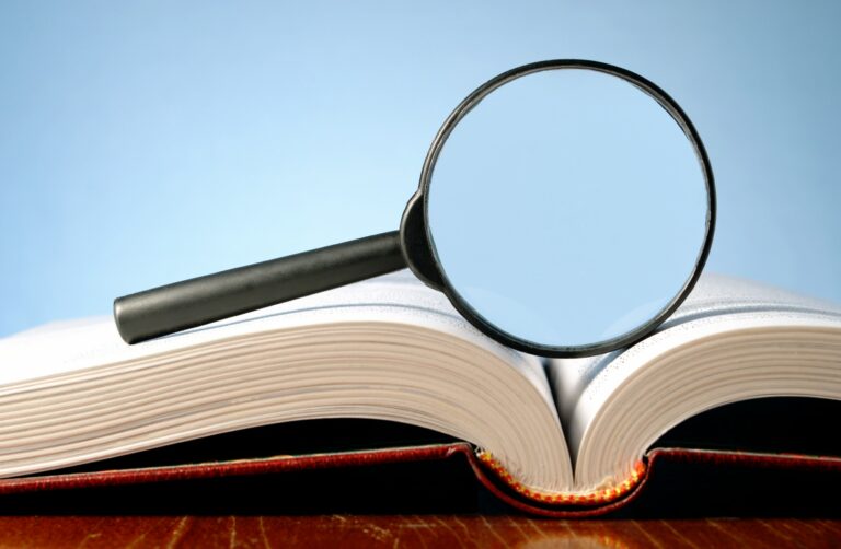 book and a magnifying glass on a blue background