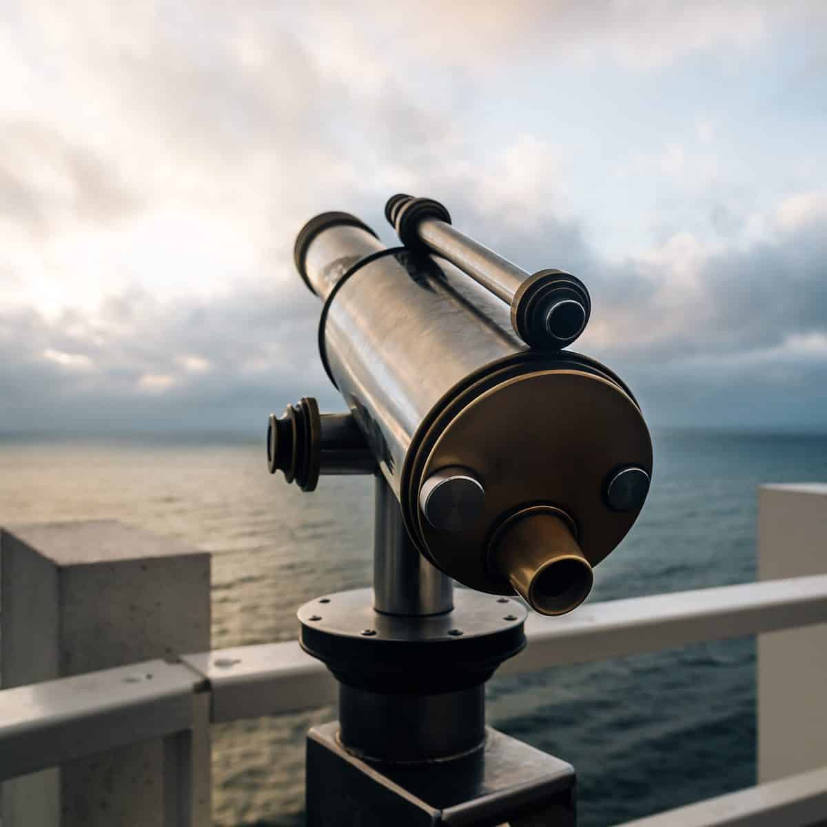 Hand held telescope on the pier over the sea at sunset