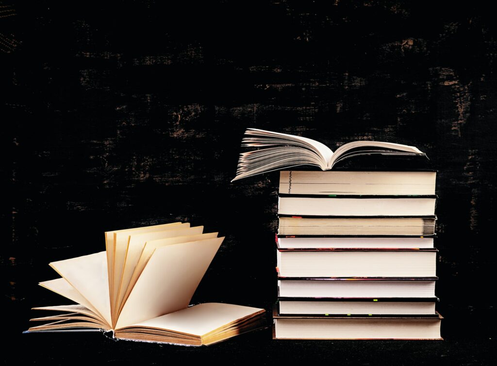 Stack of different books on dark background. Knowledge concept.